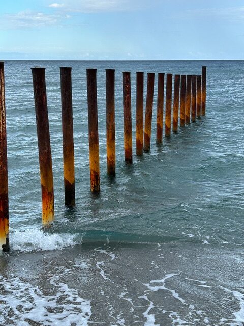 Reihe von Pfeilern im Meer, die eine klare Linie ins Wasser führen – Sinnbild für den Weg und die Entwicklung unseres Unternehmens.